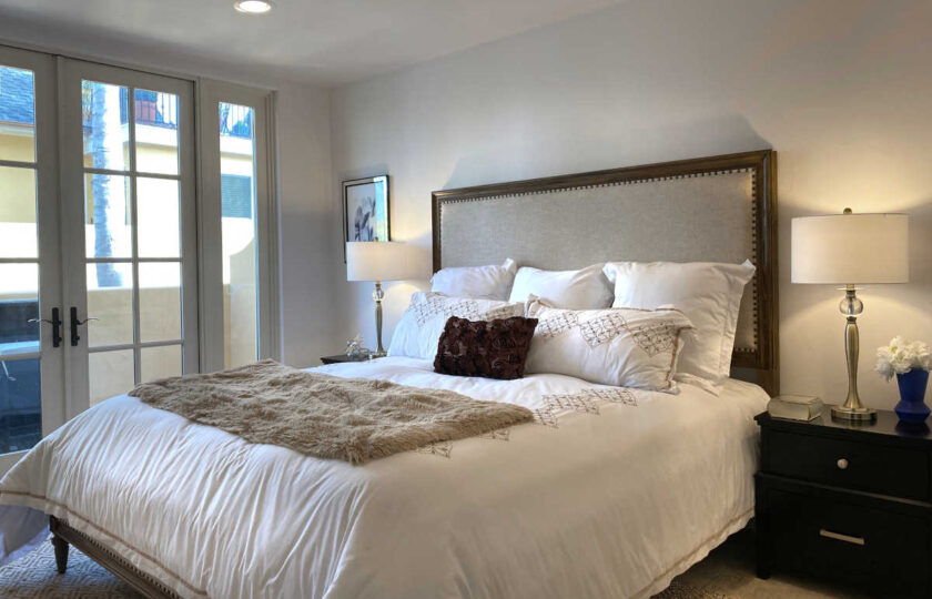 Master bedroom facing California King bed with wood and cushioned headboard, white bedding
