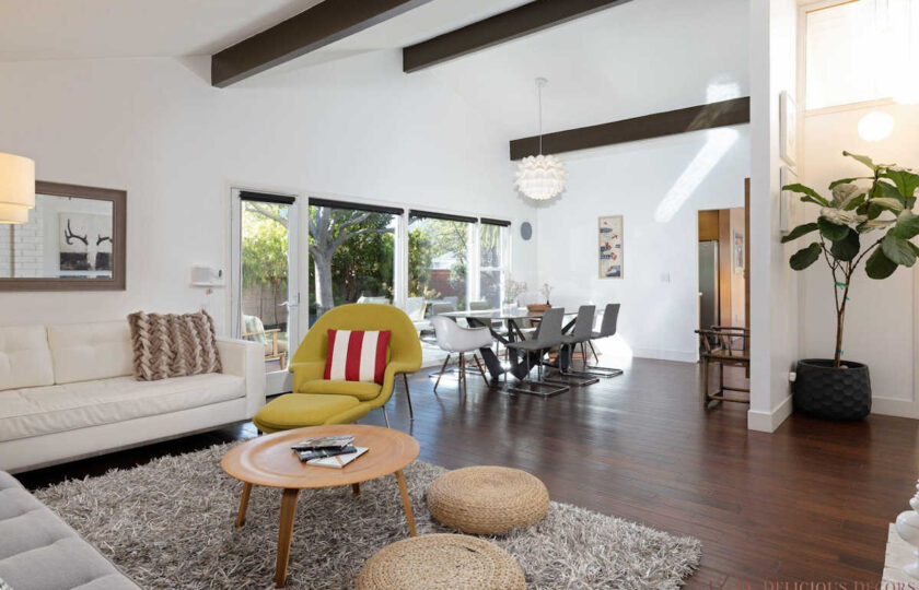 Mid-century modern living room scene facing yellow accent chair and dining room behind
