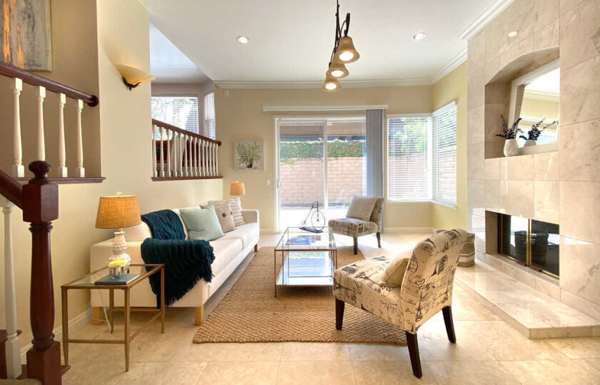Family room with warm lighting and ivory furniture accompanied with glass coffee table and jute rug