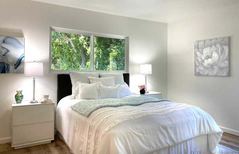 master bedroom with king size white bed and two white nightstands with table lamps