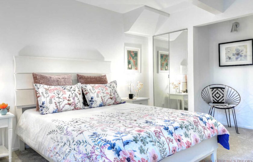 Second guest bedroom, featuring white wood queen bed with blue flower bedding and rod iron accent chair in the right corner