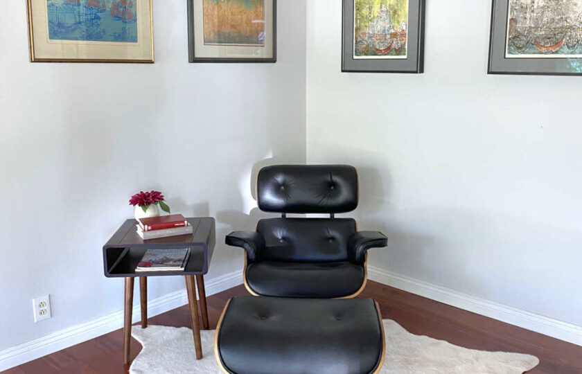 Black leather and walnut chair with foot rest on cowhide rug
