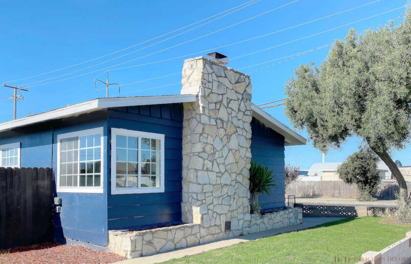 Exterior shot of the property with blue paint and stone chimney