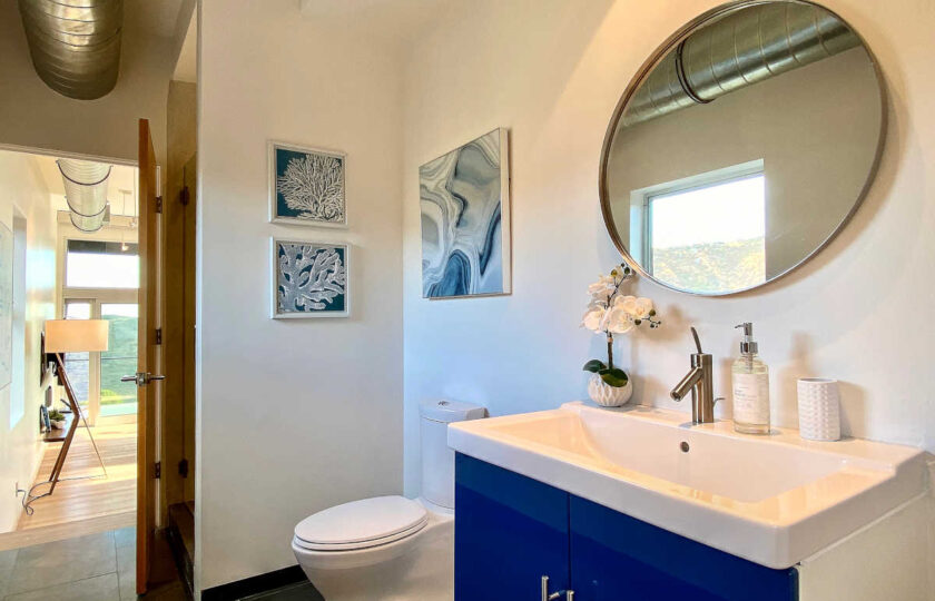 Hallway bathroom with blue patterned art hung to match the vanity cabinets