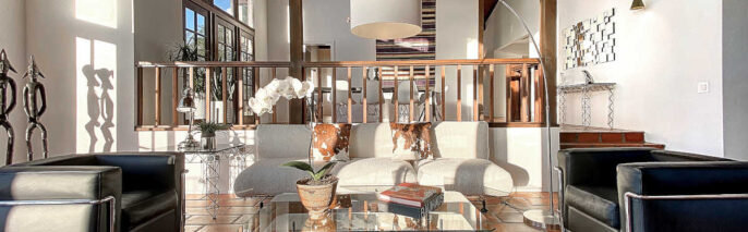 Living room facing two blue leather contemporary accent chairs, chrome and glass coffee table, and beige sofa