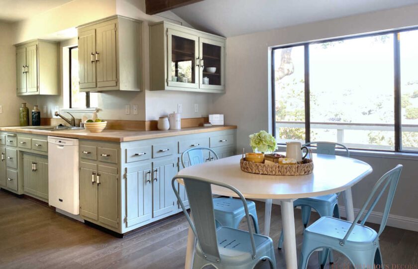 Kitchen with white wood kitchen table, light blue metal chairs, and cabinetry in the background