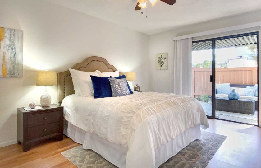 Guest bedroom facing a beige headboard with bronze nail-heads and white, fluffy bedding with blue accent pillows