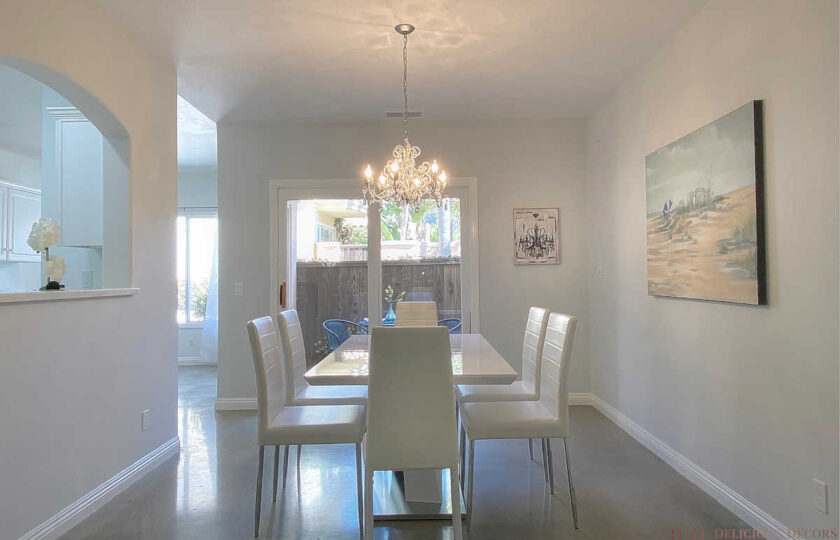 Dining room with acrylic and chrome contemporary dining table and straight legged white leather dining chairs