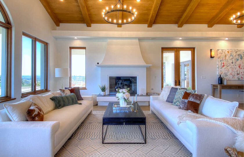 Home staging featuring rustic dark wood coffee table between a two pure-white upholstered sofas with wraparound arms