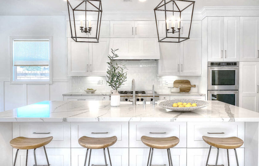 Backless, sloped bart stools with rod iron base in front of oversized marble kitchen island