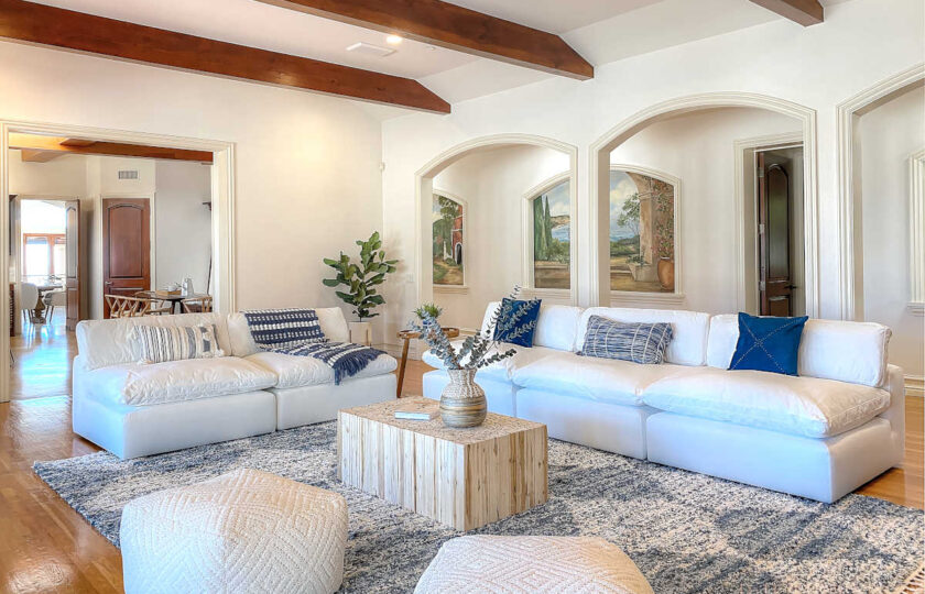 Open arches and dark beams on the ceiling add character to this family room with L shaped sofa seating in this modern traditional Malibu compound.