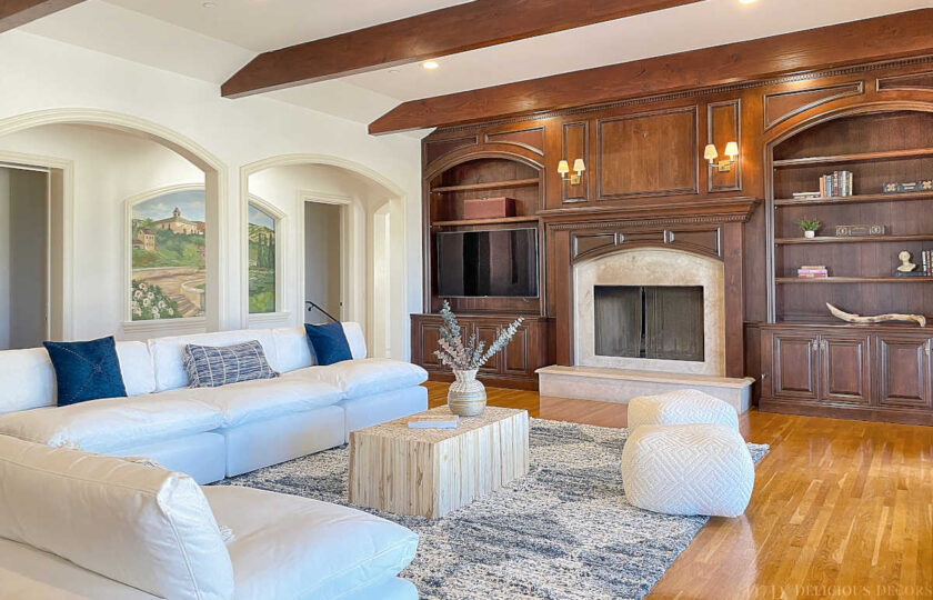 Dark wood paneled wall with center fireplace has an L shaped seating area in a more casual family room.
