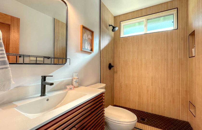 Beautifully remodeled bathroom with wood panels along the shower and vanity.