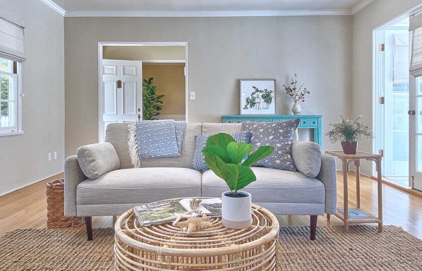 Circular bamboo coffee table in front of an ivory two-cushion mid-mod sofa, all over a jute rug