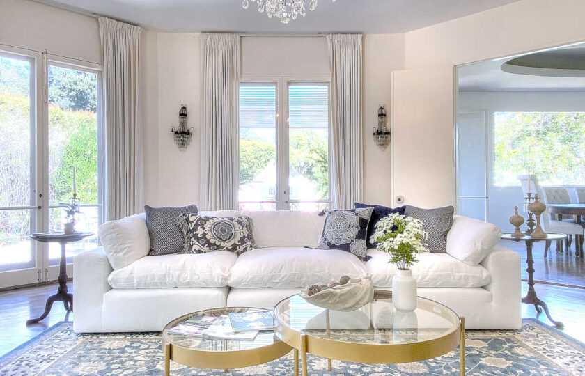 Beautiful sofa arrangement with crystal chandelier above and sconces beyond