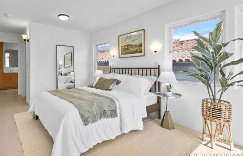 Primary bedroom staging with plenty of layering through a thin jute rug, turned down bedding, art above headboard, and antiqued gold standing mirror behind