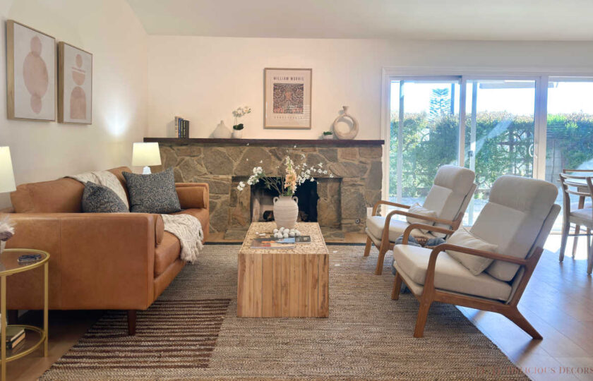 West Pasadena home staging featuring a tailored tan leather sofa, raw block-wood coffee table, and wood-framed accent chairs in front of a classic stone fireplace.