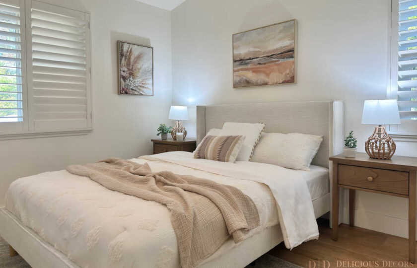 West Pasadena home staging in a bright, calming primary bedroom featuring a light upholstered bed, layered neutral textures, wooden nightstands with woven rattan lamps, and bright plantation shutters.