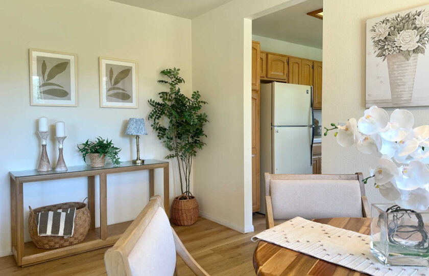 Relaxed, cottage-inspired design in the guest house dining space, featuring a round wood table and woven accents leading into the kitchen for this Santa Ynez luxury estate staging.