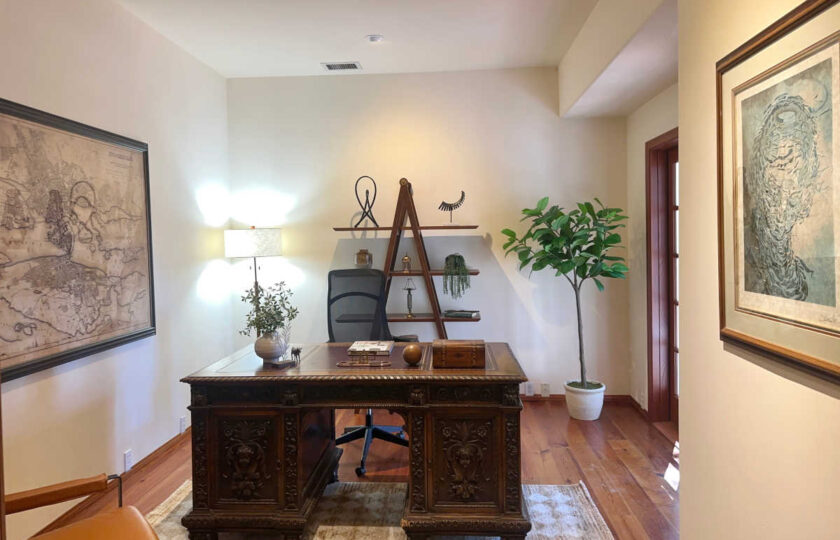 Santa Ynez luxury estate staging in an executive office, featuring an antique mahogany desk with ornate carvings balanced by a smooth saddle leather guest chair.