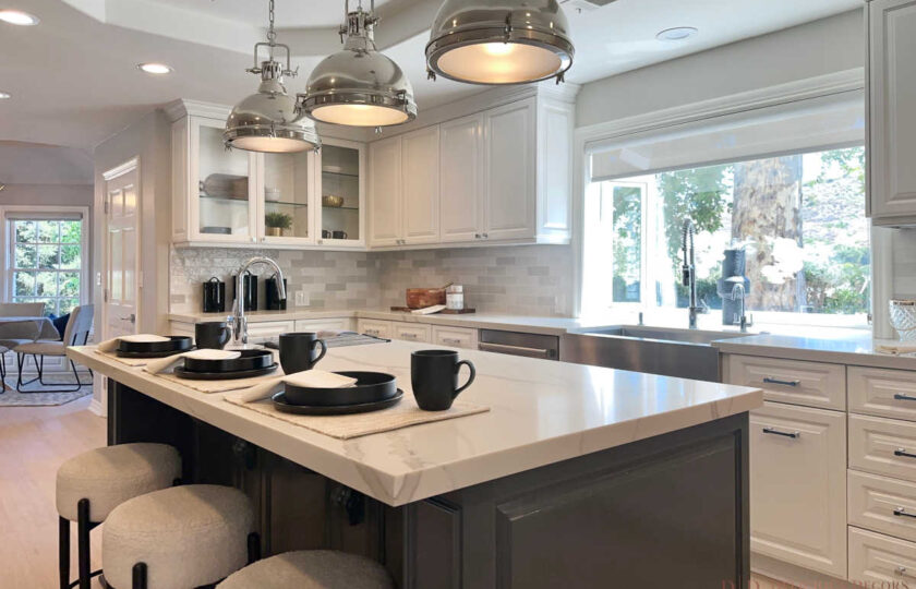 Modern transitional kitchen staging showcasing white cabinetry, stone countertops, bouclé barstools, and mountain view window.