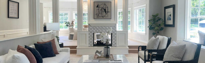 Modern transitional staging in Westlake Village formal living room featuring dual-sided fireplace, white sofa, and black accent chairs.