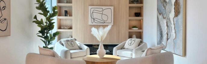 North Hollywood modern organic staging featuring four bouclé armchairs arranged around a round wood coffee table with custom light oak wall paneling and built-in shelving.