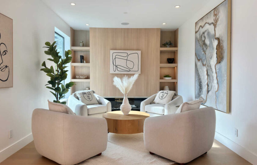 North Hollywood modern organic staging featuring four bouclé armchairs arranged around a round wood coffee table with custom light oak wall paneling and built-in shelving.