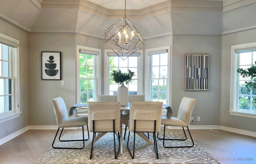 Breakfast nook staged with round dining table, bouclé chairs, geometric pendant light, and black-and-white artwork in a bay window.