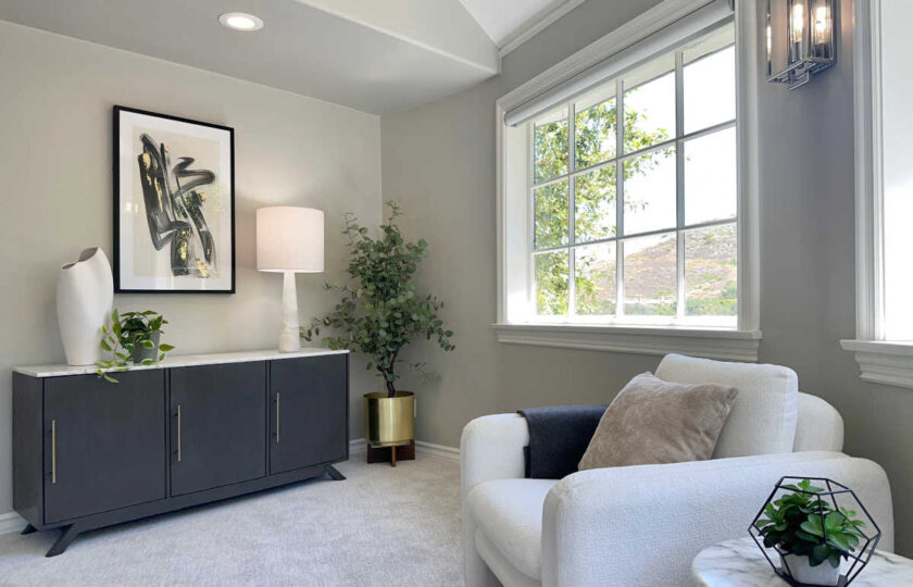 Staged lounge nook featuring plush bouclé armchair, dark credenza, marble side table, and mountain view window.