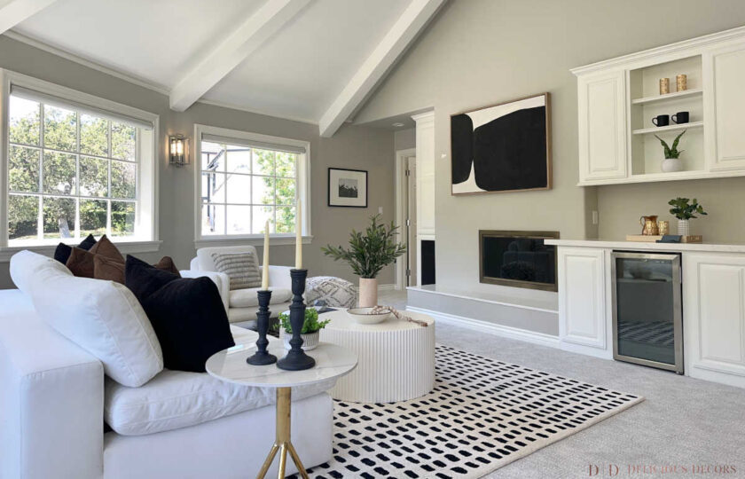 Upstairs bonus room featuring vaulted white beams, built-in beverage bar, white sofa, and black abstract art.