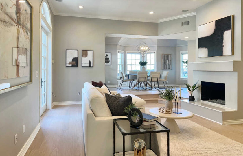 Open family room staging featuring cream sectional, stone coffee table, fireplace, and view into elevated dining nook.