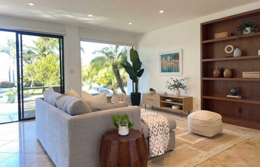 Mid-Century Modern living room staging in Malibu featuring grey sectional, low wood console, and built-in oak shelving.