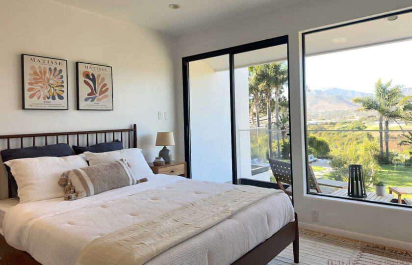 Modern Malibu bedroom staging with spindle headboard, Matisse art prints, neutral bedding, and ocean-facing window views.