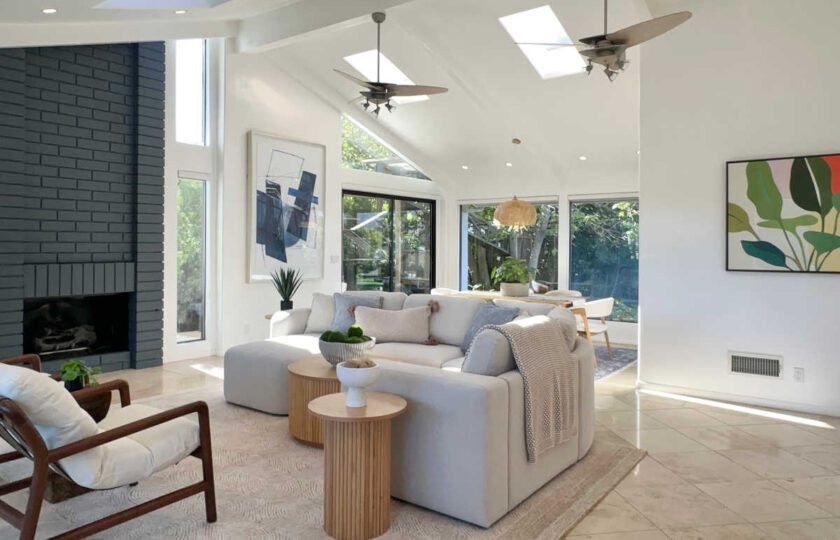 Light-filled Malibu great room featuring skylights, dark accent fireplace, white sectional, and natural wood furniture accents.