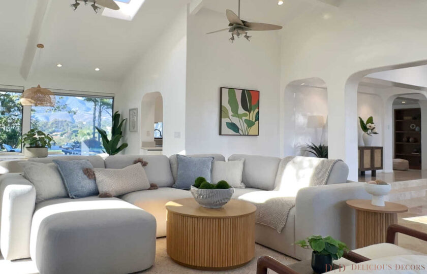 Open-concept Malibu living room staging with modular cream sectional, round tamboured coffee table, and vaulted ceilings.