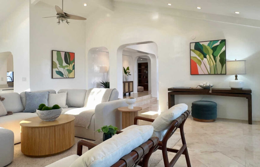 Malibu living room view showcasing leather sling chairs, fluted side tables, tropical artwork, and arched architectural details.