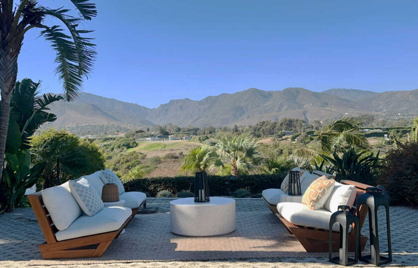 Mid-Century Modern staging in Malibu outdoor lounge area featuring teak seating, concrete coffee table, and mountain views.