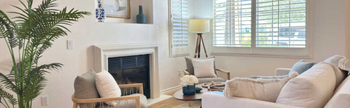 Elegant formal living space styled with Dos Vientos Home Staging, featuring woven accent chairs, a potted palm, and soft blue decor accents.