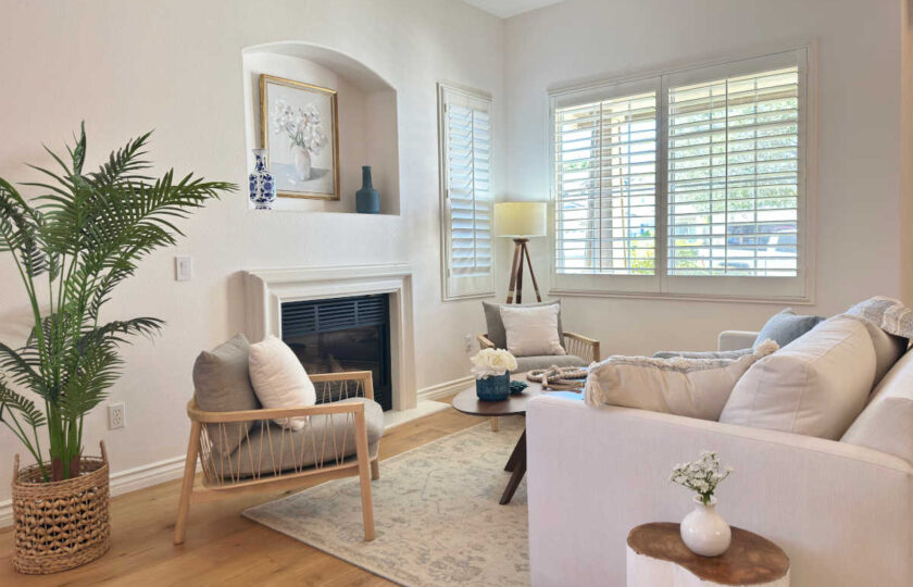 Elegant formal living space styled with Dos Vientos Home Staging, featuring woven accent chairs, a potted palm, and soft blue decor accents.