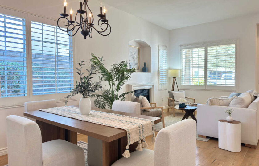 Open-concept dining area featuring a wooden table, upholstered chairs, and a wrought-iron chandelier styled with Thousand Oaks home staging.