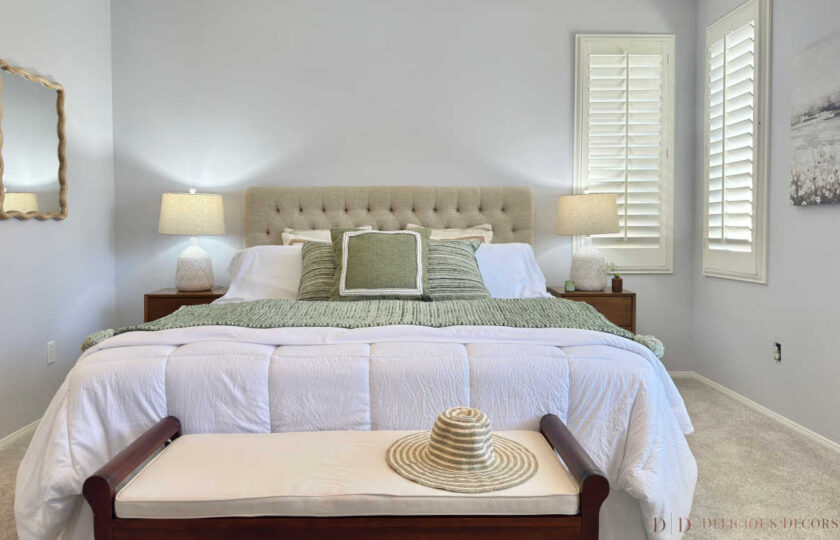 Primary bedroom suite staging featuring a tufted upholstered headboard, sage green throw blanket, white ceramic lamps, and a wooden end-of-bed bench in Thousand Oaks.