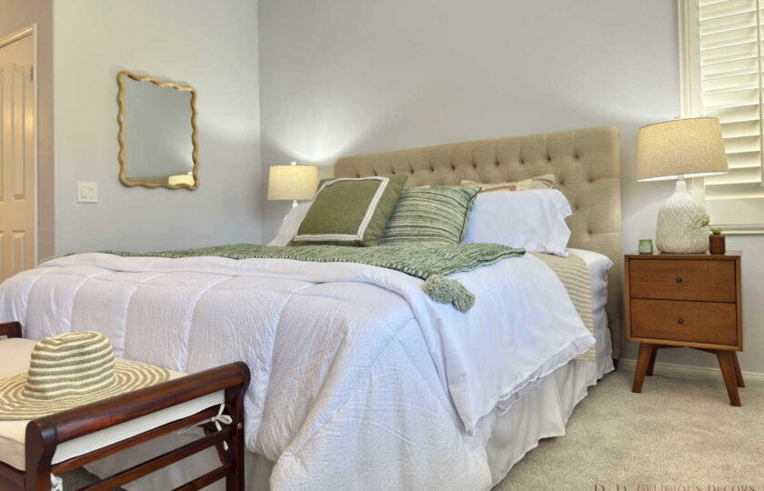 Primary bedroom staging with mid-century wood nightstands, a gold wavy mirror, crisp white bedding, and green accent pillows in Thousand Oaks.