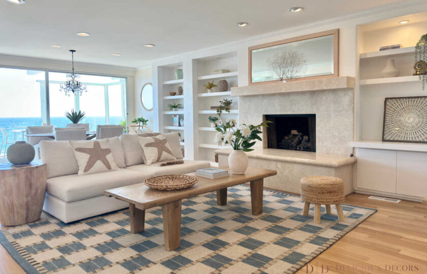 Cozy oceanfront family room staged with a white sectional sofa, starfish throw pillows, a rustic wooden coffee table, and a blue patterned rug.