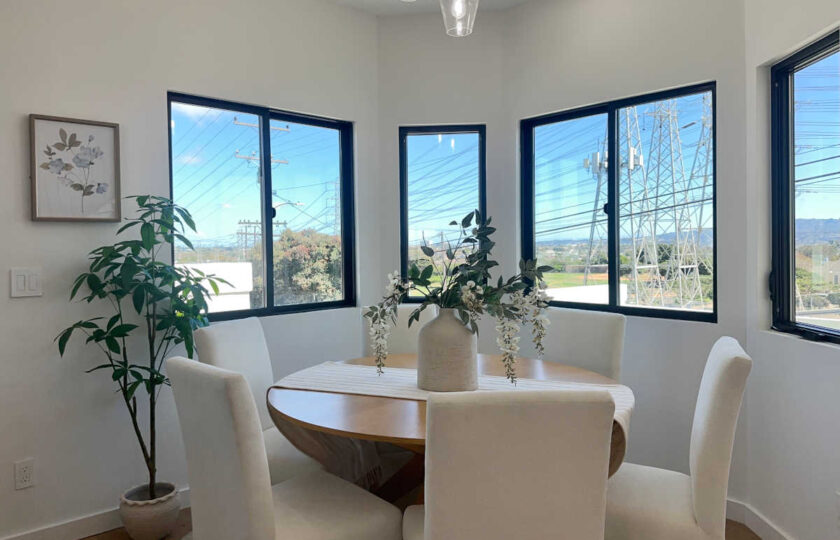 Staging Redondo Beach Modern Coastal with round oak table, ivory upholstered chairs, and bright sunny windows.