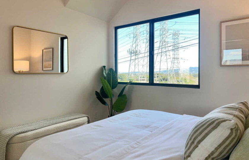 Staging Redondo Beach Modern Coastal featuring bright window light, white bedding, floor plant, and framed art.