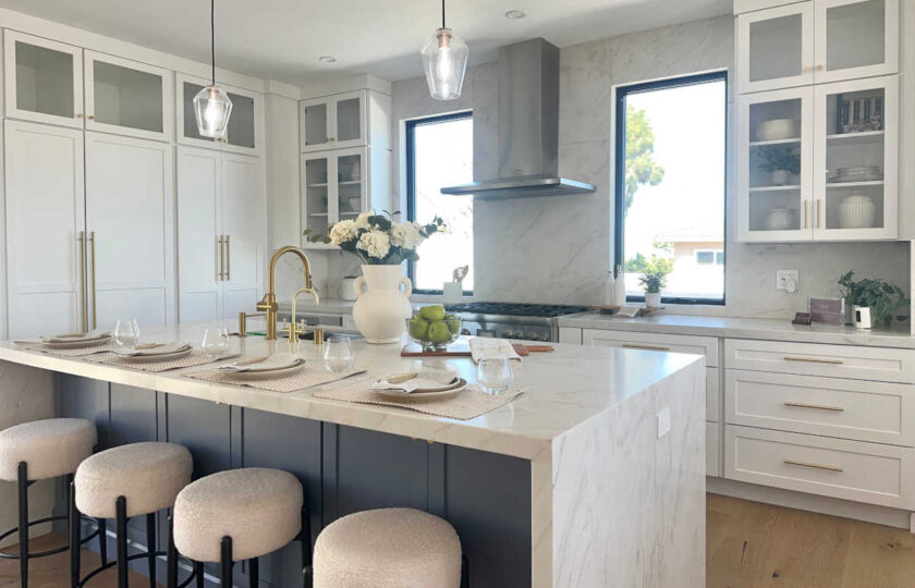 Staging Redondo Beach Modern Coastal featuring white cabinets, marble waterfall island, navy base, and gold faucet.