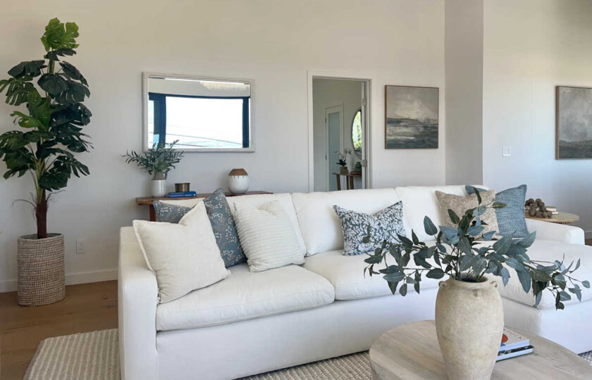 Redondo Beach Modern Coastal featuring white sectional, blue pillows, wood coffee table, and indoor tree.