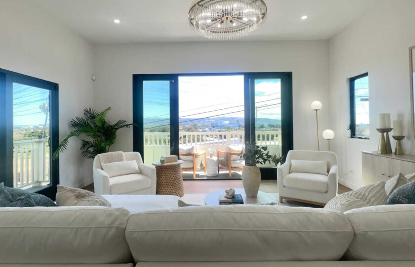 Staging Redondo Beach Modern Coastal featuring white sectionals, bouclé chairs, and glass doors to balcony.