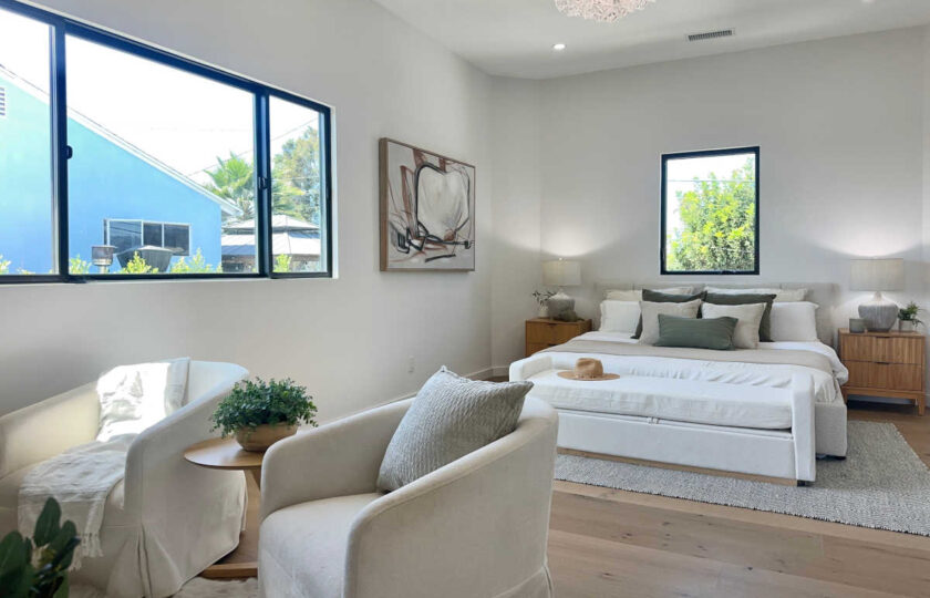Staging Redondo Beach Modern Coastal with upholstered bed, ivory lounge sitting area, and light oak floors.